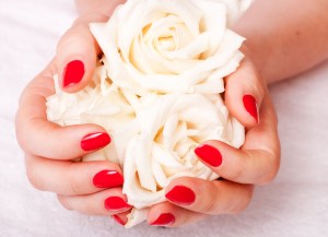 Hands with red nails holding white roses | Nail salon in Leighton Buzzard